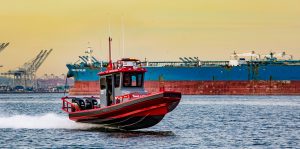 Red and gray Tow Boat U.S. Ambar boat moving fast on the water